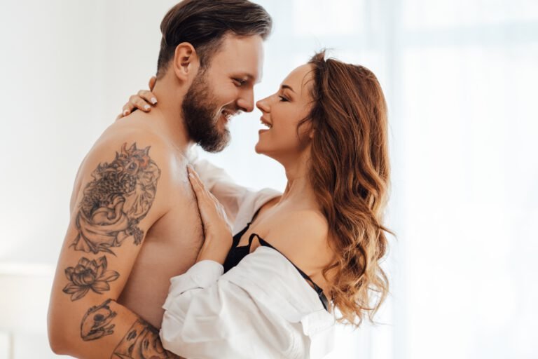 Sexy smiling passionate young couple in underwear embracing, looking each other