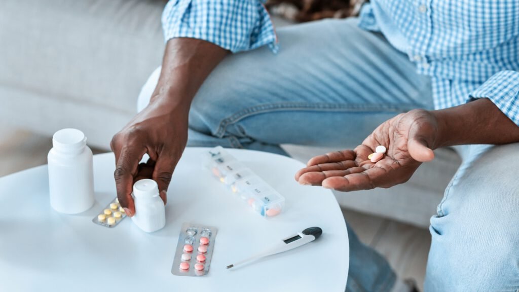 Viral diseases treatment. Unrecognizable African American man with different meds at table indoors